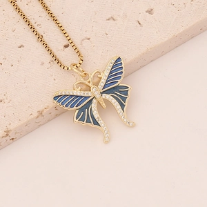 Macro view of golden butterfly necklace with blue enamel wings and sparkling zircon detail