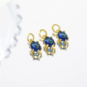 Macro shot of three oval blue zircon pendants with gold metal settings and reflections