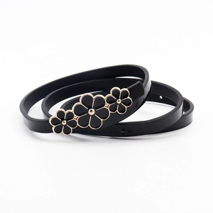 Detail of a thin black belt featuring a metallic floral buckle for dresses and sweaters