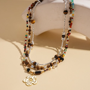 Tiger eye beaded necklace with a golden flower pendant on geometric stone display