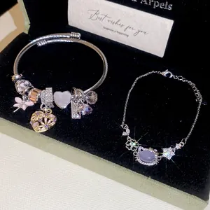 Detailed macro shot of silver charm bracelet with pink butterfly and engraved love pendants