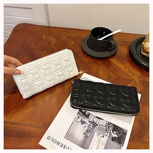 Close-up of long quilted faux leather wallets in black and white on a wooden table