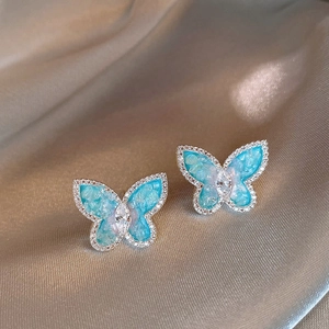 Vue macro de boucles d'oreilles papillon avec ailes en résine bleue et zircon