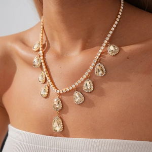 Gros plan de cristaux de champagne en forme de goutte sur un collier doré de luxe