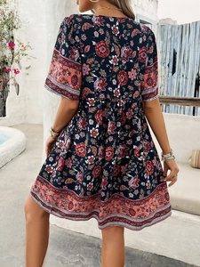 Rear view of a floral short sleeve A-line dress with V-neck back in outdoor setting