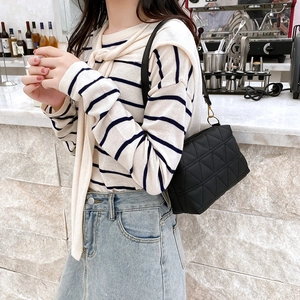 Fashionable black quilted crossbody bag with golden hardware shown in a street style setting