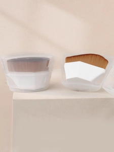Detail of hexagonal foundation brush with white handle and transparent storage case