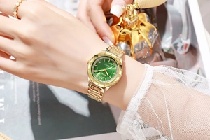 Gros plan d'une montre de luxe dorée pour femme avec cadran vert et lunette