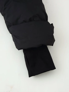 Detail of black puffer jacket cuff with ribbed windproof sleeve and thumbhole design