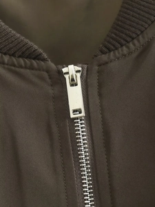Gros plan du zip métallique argenté et du col en tricot de la veste marron