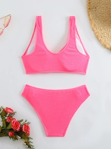 Flat lay of pink ribbed bikini with sunglasses, straw hat, and roses for a summer vibe