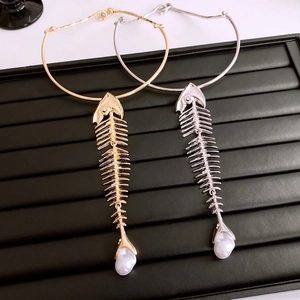 Detailed view of gold and silver fishbone necklaces with pearls on a black jewelry tray