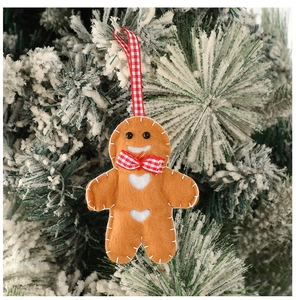 Détail de décoration de bonhomme en pain d'épices en feutre avec nœud rouge sur sapin