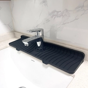 Macro view of black silicone faucet splash guard with wavy drainage grooves on marble counter