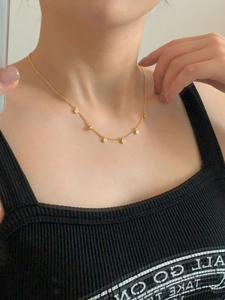 Detail of a minimalist gold necklace with round zircon pendants on a model's neck