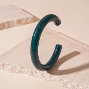 Macro view of dark green acrylic resin open bangle with imitation jade marble texture