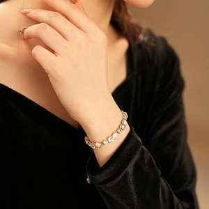 Détail d'un bracelet doré ajustable avec pierres blanches sur le poignet d'un modèle