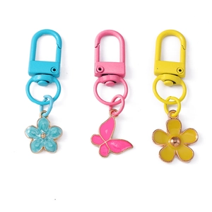 Three colorful flower and butterfly metal keychains in blue, pink, and yellow floral designs