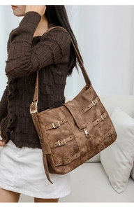 Detail view of large brown vintage tote bag with decorative metal buckles and wide strap