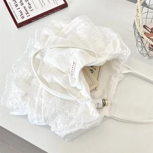 Dettaglio delle balze in pizzo bianco e ricami su una borsa shopping stile romantico