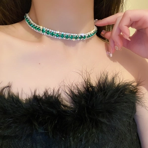 Nahaufnahme der smaragdgrünen Halskette mit weißen Diamanten am Hals des Models