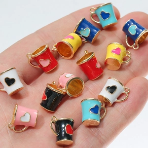 Macro view of colorful heart teacup enamel charms held in hand for size reference