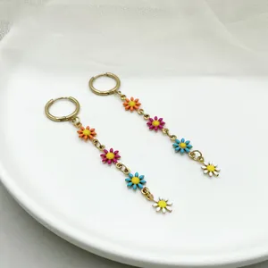 Detail of floral tassel earrings with colorful enamel petals and gold circular hoops