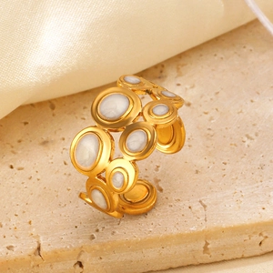 Golden hollow geometric open ring with white enamel inlay on natural stone background