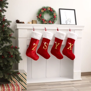 Dettaglio di calze di Natale in velluto rosso con lettere dorate su un camino bianco
