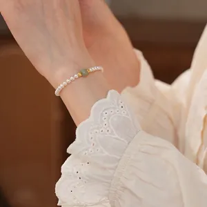 French vintage style pearl bracelet with green jade bead on a female wrist