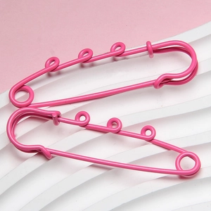 Close-up of pink lacquer coated 6cm safety pins with triple loop decorative metal design