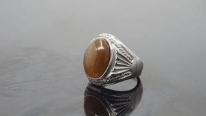 Detailed side view of vintage silver ring featuring an oval tiger eye stone and intricate carving