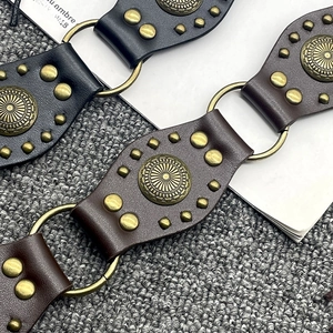Detailed macro shot of vintage y2k leather belt featuring brass studs and metal ring links