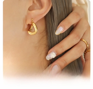 Detailed view of 18k gold plated titanium steel twisted C-shape hoop earring on ear