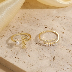 Macro detail of 14K gold plated rings with Love design, pearls and sparkling zircons