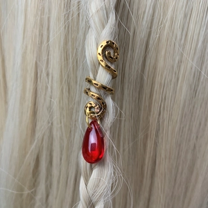 Detailed close-up of a vintage gold spiral hair accessory with a red teardrop pendant