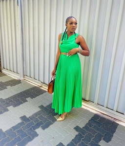 Detail van een smaragdgroene mouwloze geplooide maxi-jurk met bruine smalle riem