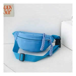Detail of sky blue canvas waist bag featuring woven purple zip pull and nylon strap