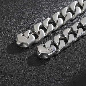 Detailed close-up of polished silver stainless steel Cuban link chain on a black background