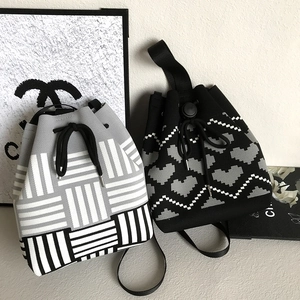 Detail of grey and white knitted drawstring bucket bags with heart pattern texture