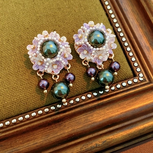 Macro shot of flower pearl earrings with dark green core and purple sequin petals