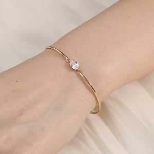 Close-up of minimalist gold-plated bracelet with oval zircon stone on wrist