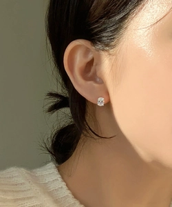 Close-up of minimalist sterling silver stud earring with oval cubic zirconia on model