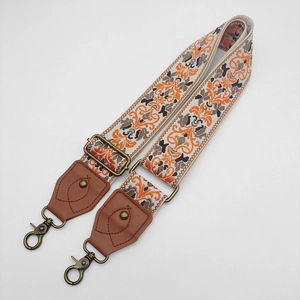 Close-up of bohemian embroidered bag strap with vintage bronze metal hooks and leather ends