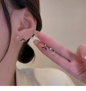 Close-up of elegant black and gold whale tail stud earrings set with sparkling crystals