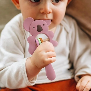 Detailed shot of a baby holding a purple koala silicone teether with colorful rings