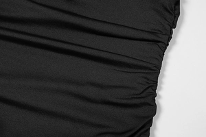 Close-up of black ruched fabric texture on a fitted dress with elegant draped pleats