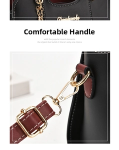 Detail of gold metal hook and red-brown leather strap on black bag with white stitching