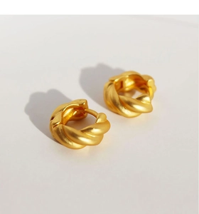 Nahaufnahme von gedrehten Gold-Creolen mit hochwertigem, matt gebürstetem Metall-Finish
