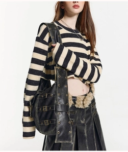 Detail of black leather crossbody bag featuring silver metallic buckles and grommets